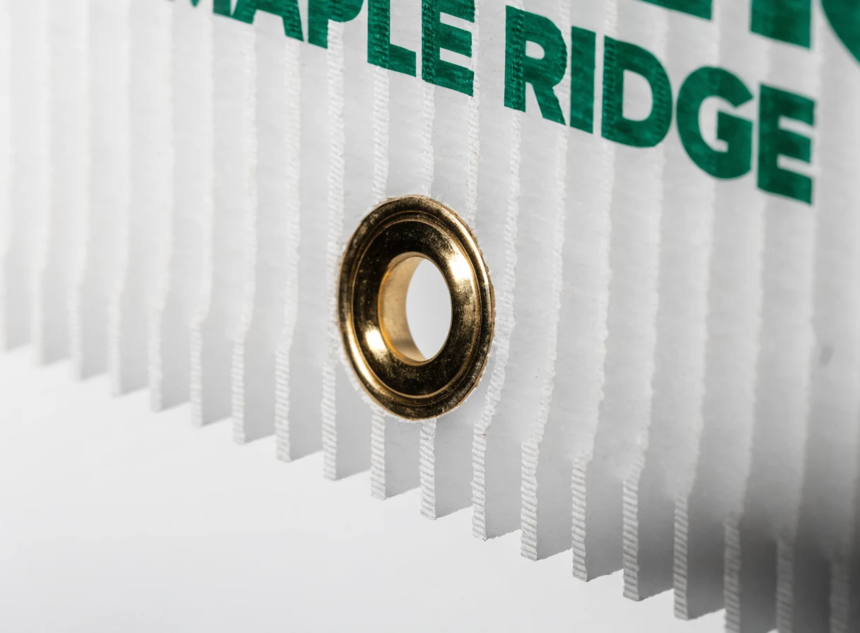 Cut edge of a coroplast panel showing the internal flutes and a brass grommet